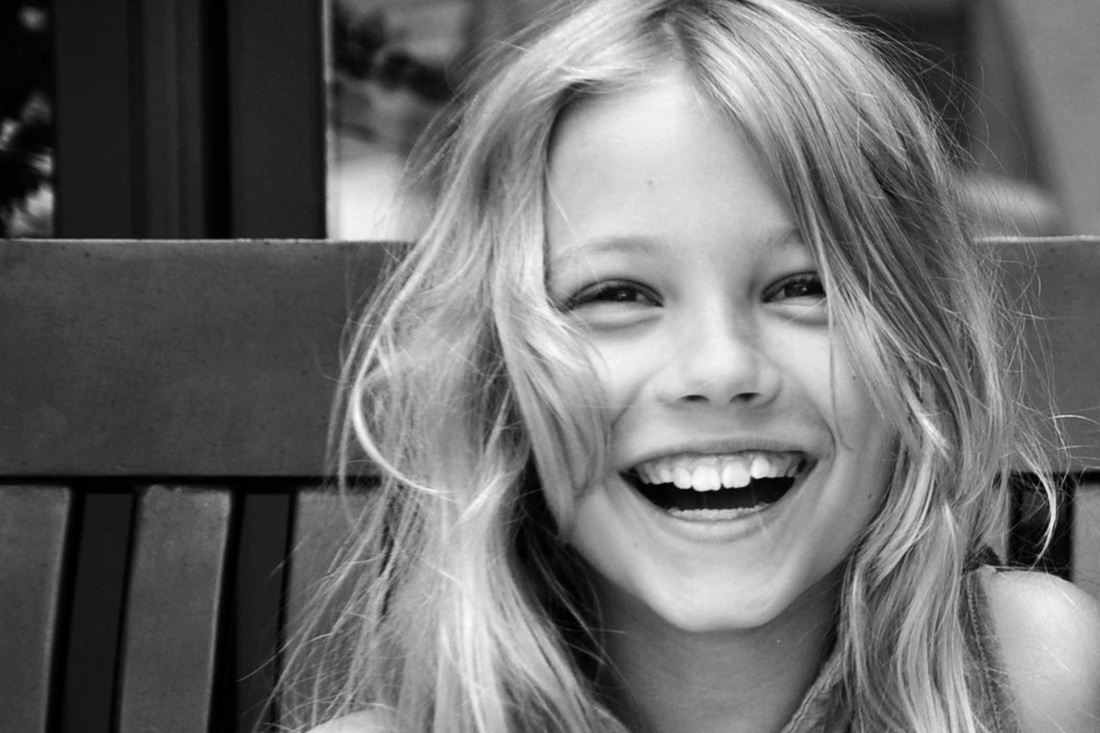 Black-and-white portrait of a child laughing on a bench