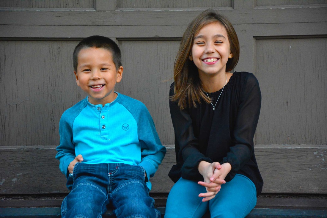 Two children smiling on a wooden bench